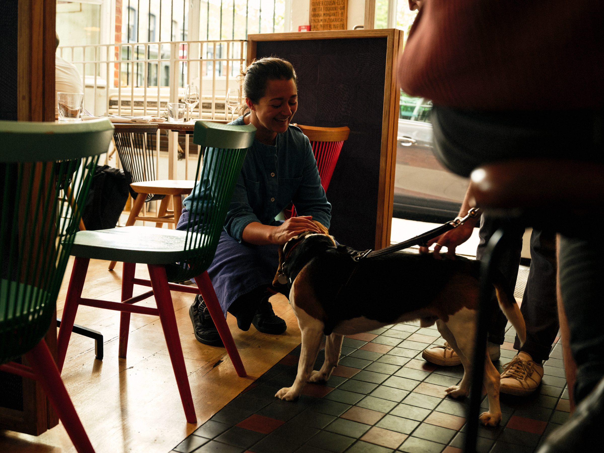 A server crouching to greet a guest and their dog
